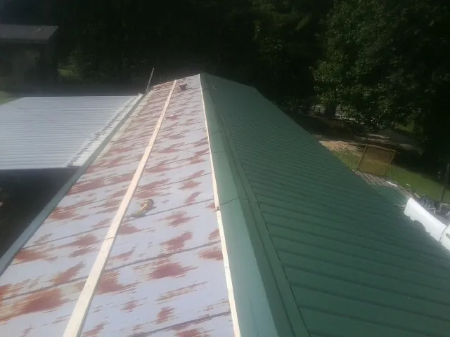 Old rusted panels beside newly installed green metal roofing — Wind Damage Roof Repair by Roofing Brothers in Sugar City