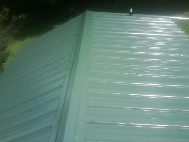 New green metal panels meeting at the ridge of a roof — Flat Roof Repair work by our crew in Sugar City