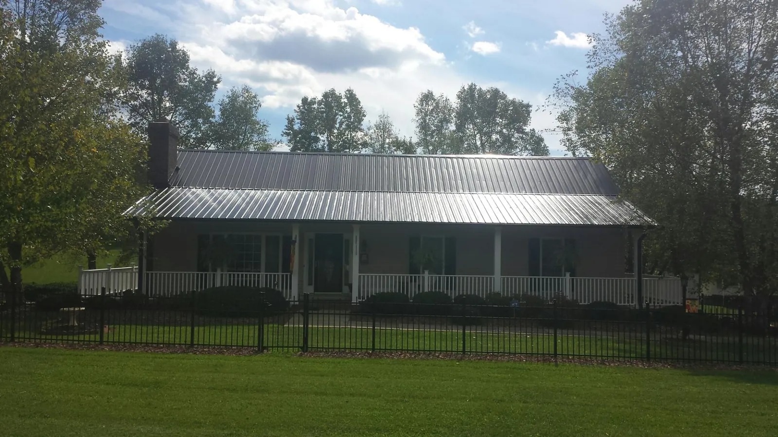 Gray metal roof on a brick ranch with a full width front porch — Gutter Guard Installation work by our crew in Sugar City