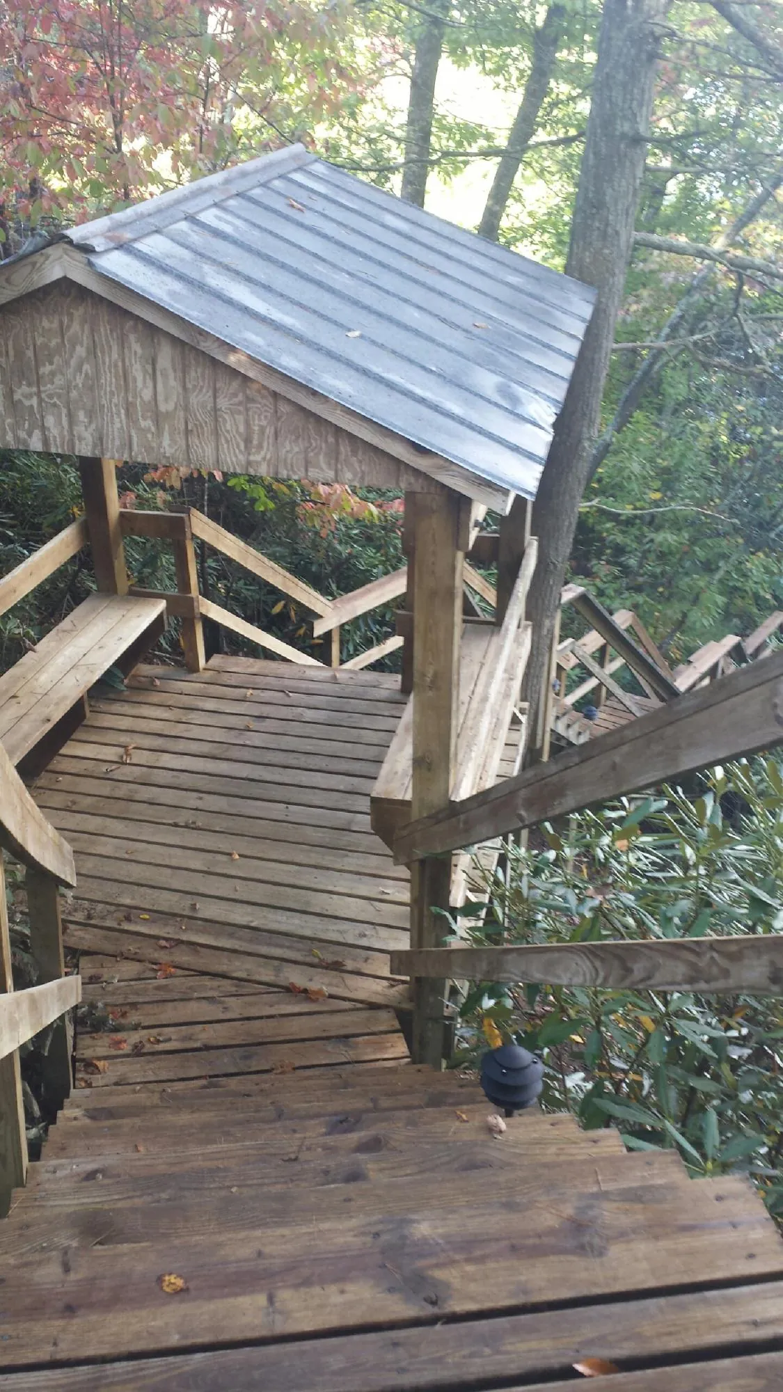 Metal roofed shelter over wooden steps on a wooded walkway — Skylight Repair & Installation work by our crew in Sugar City