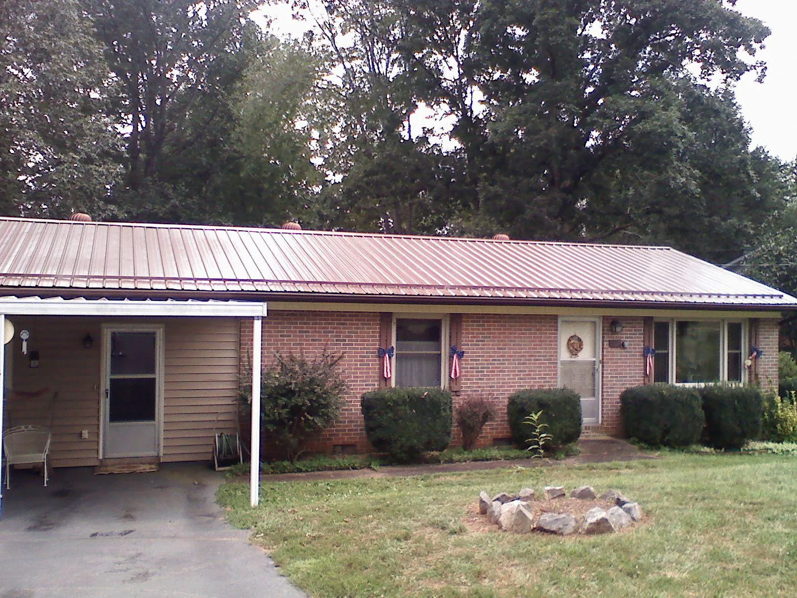 Bronze metal roof and carport on a brick ranch home — Roof Repair work by our crew in Sugar City