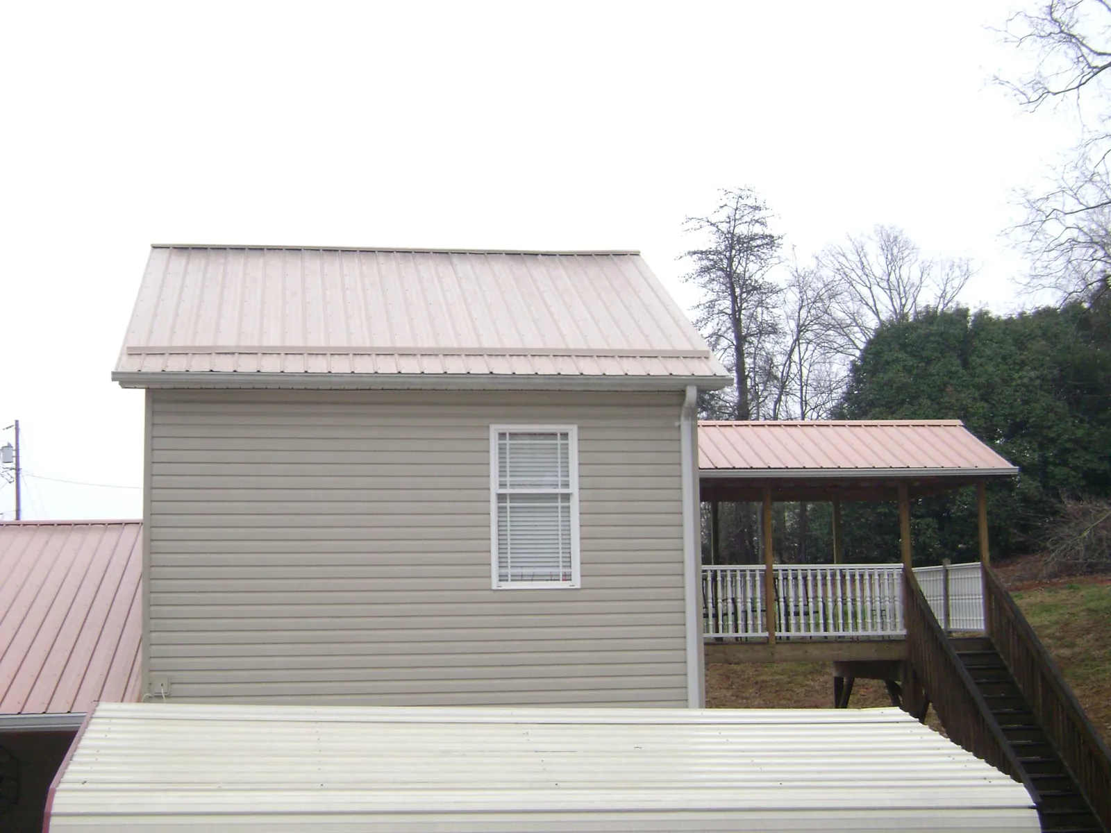 Tan metal roofs on a two story addition and attached porch, from a Roof Replacement job in Sugar City