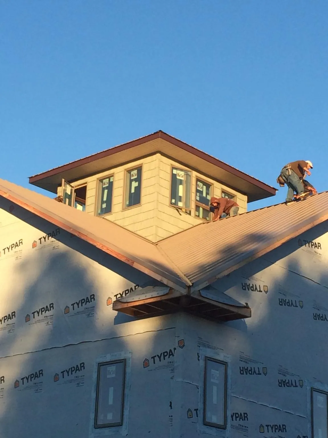Roofers working around a rooftop cupola on a new metal roof at sunset — Roof Waterproofing in Sugar City by Roofing Brothers